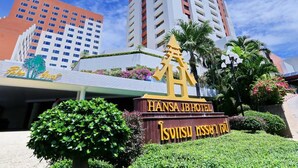 The Hansa JB Hotel sign with a traditional Thai architectural symbol, surrounded by lush greenery and palm trees. - Hansa JB Hotel (Hat Yai)