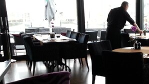 En restaurang med bord och stolar som är placerade för att skapa en bekväm matplats.