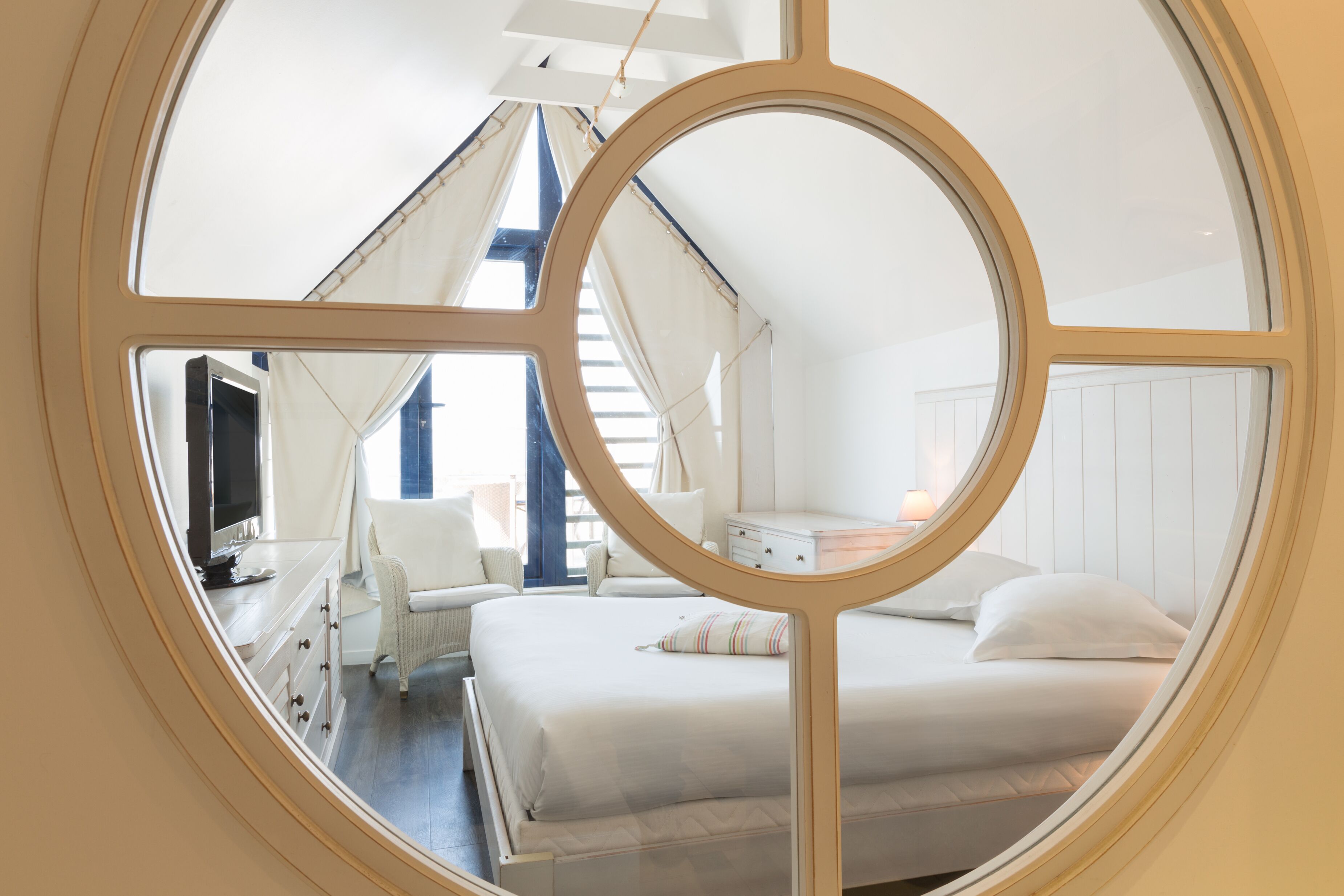A bedroom with a bed, a dresser, a chair, and a television.