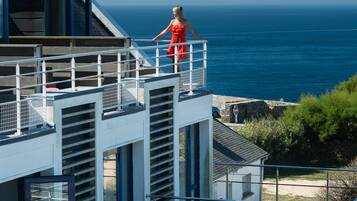 A modern building with a glass balcony overlooking the sea.
