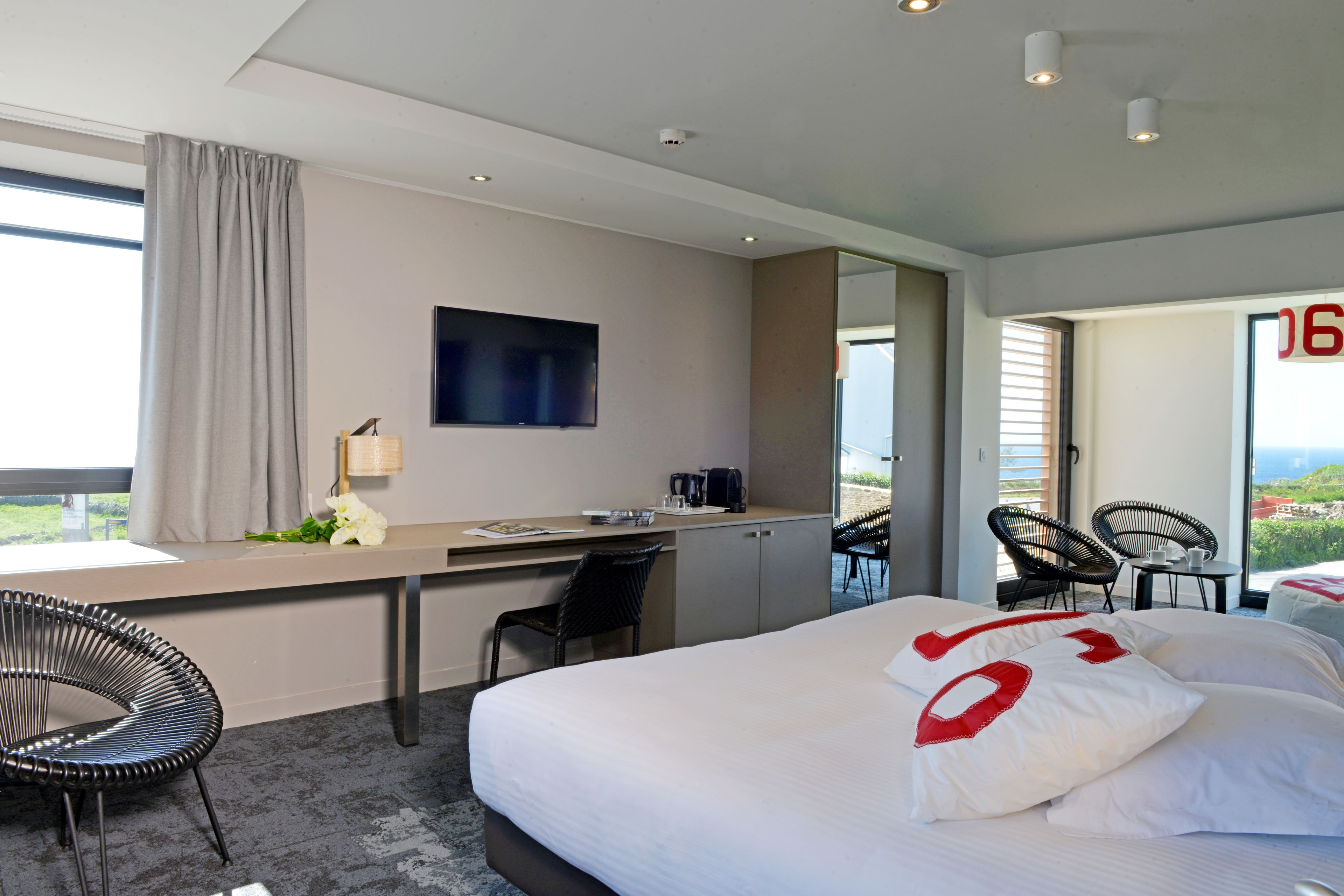 Une chambre d’hôtel moderne dotée d’un grand lit, d’un bureau et d’un balcon avec des chaises.