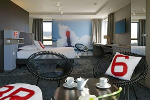 A hotel room with a bed, two chairs, a desk, a TV, and a mural of a lighthouse. - Hostellerie Pointe Saint-Mathieu (Plougonvelin)