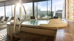 Un jacuzzi con terraza de madera, sillones reclinables, ventanas amplias y una pared de piedra.