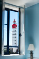 Una habitación con ventana que da a un faro.