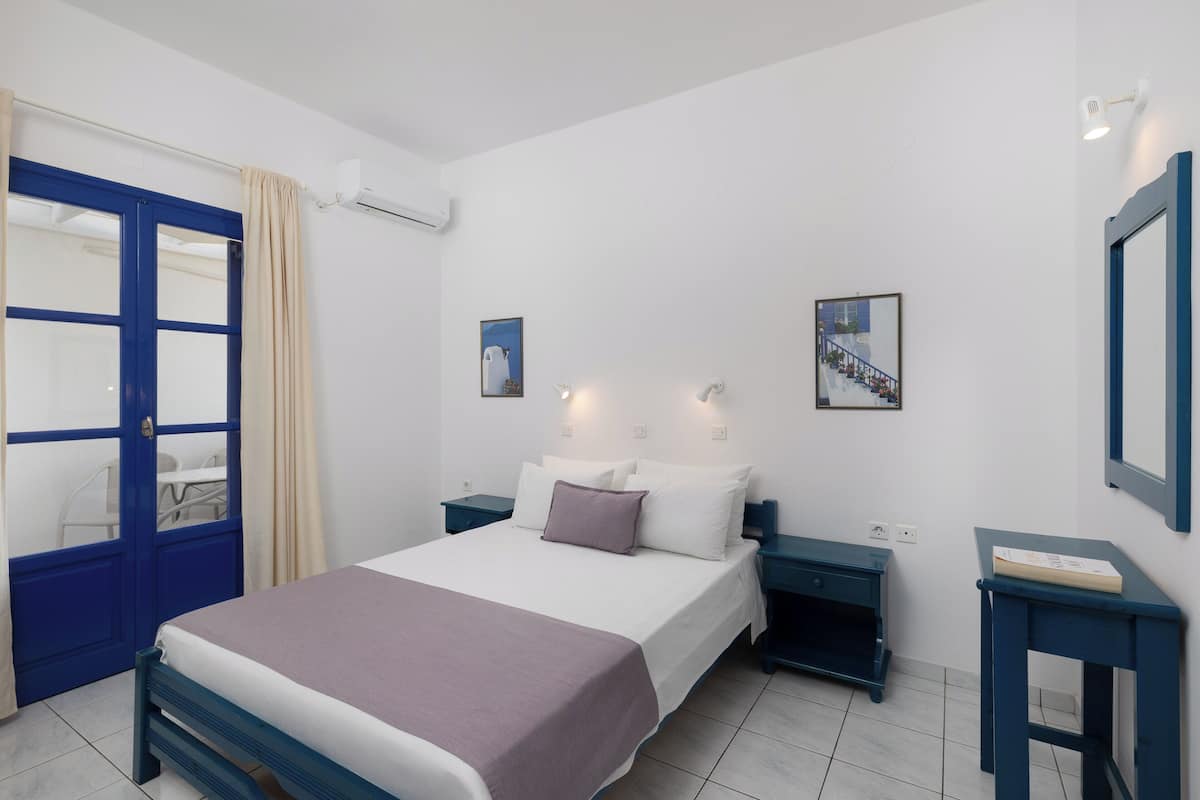 A bedroom with a bed, bedside tables, a wardrobe, and a door.