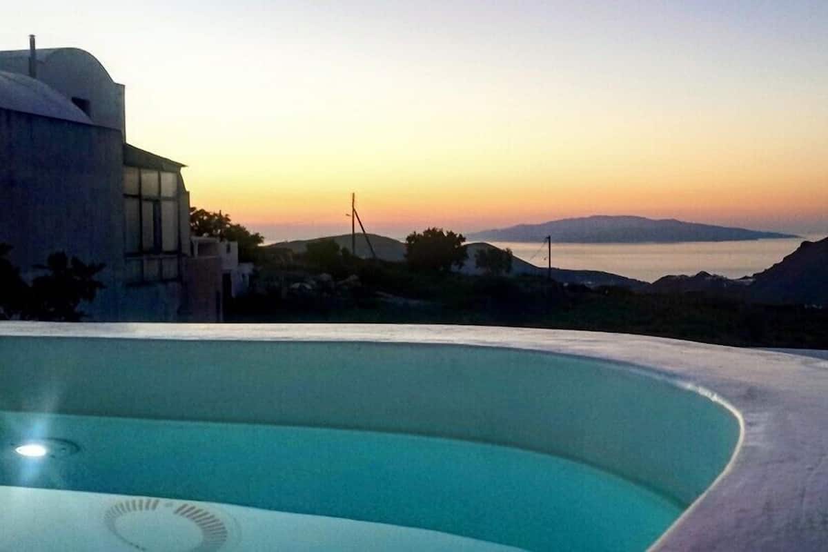 A pool with a view of a sunset and distant mountains.