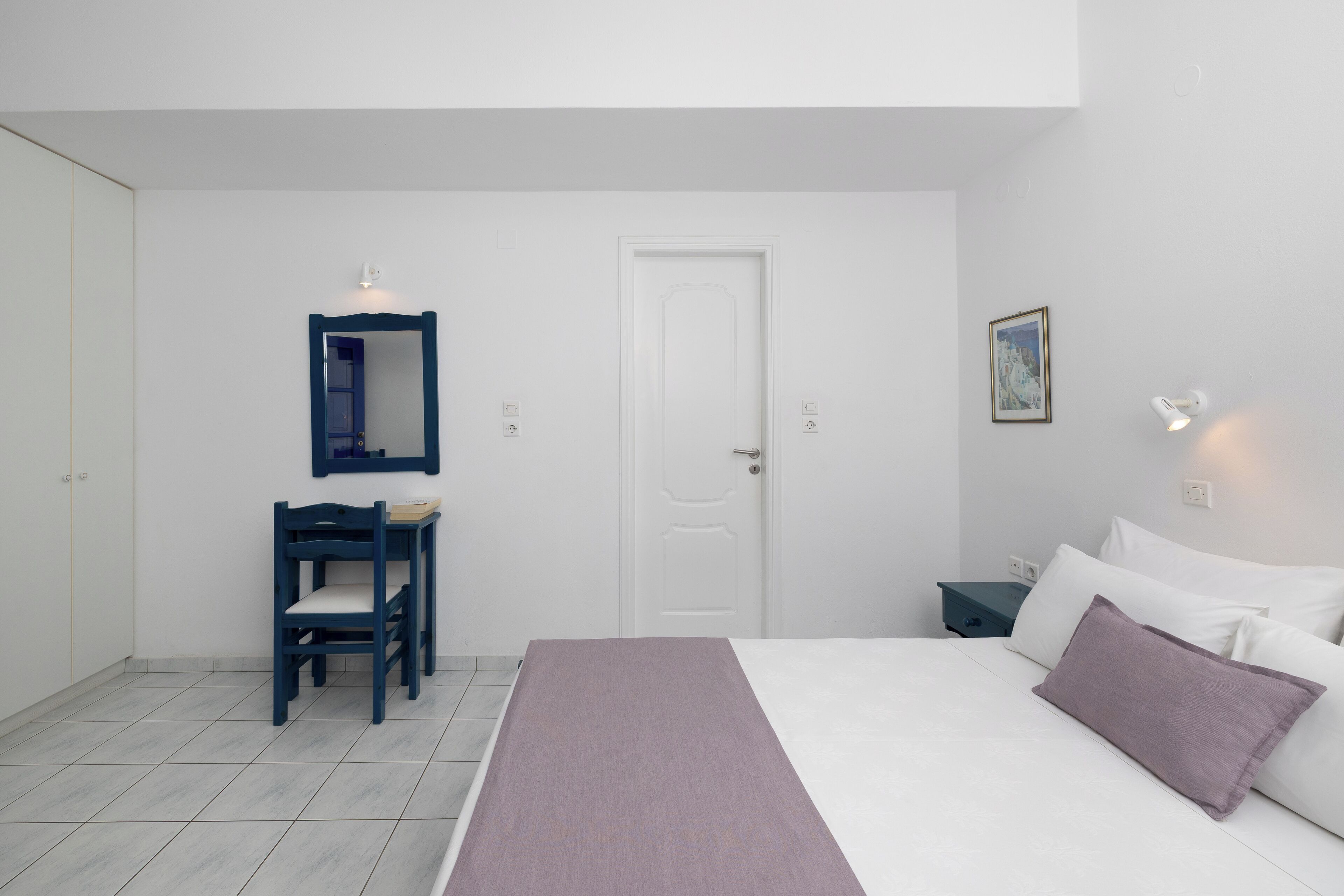 A bedroom with a bed, a desk, a chair, a wardrobe, and a door.