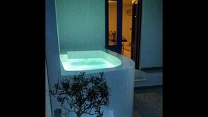 A spa area with a hot tub, a small tree, and a stone basin. - Villa Happening (Santorini)