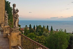 A balcony with stone statues overlooking a coastal town.