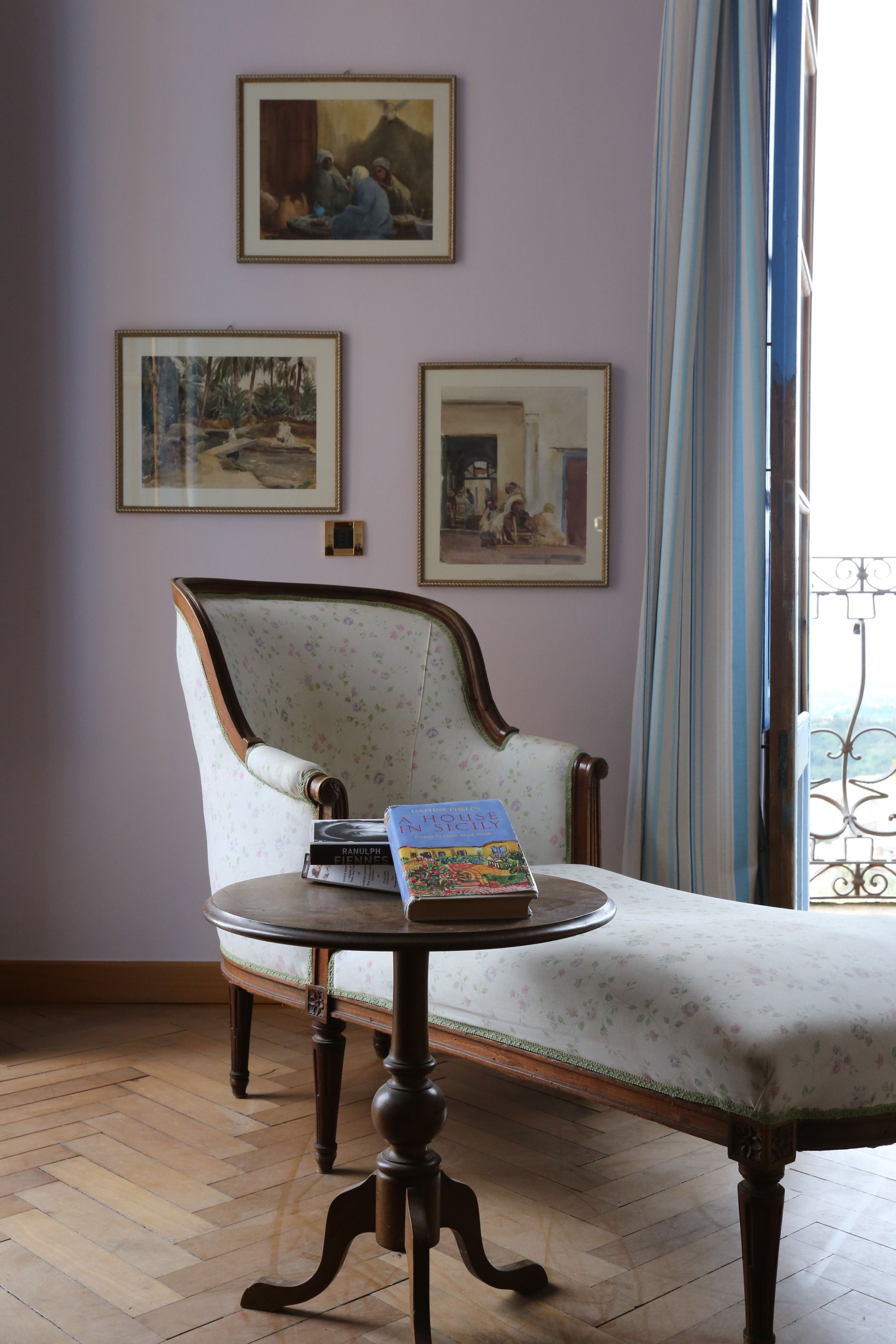 Une pièce comprenant une chaise en bois, une table ronde et deux tableaux encadrés accrochés au mur.
