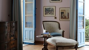 Una habitación con piso de madera, una silla, un aparador y una mesa con un libro.