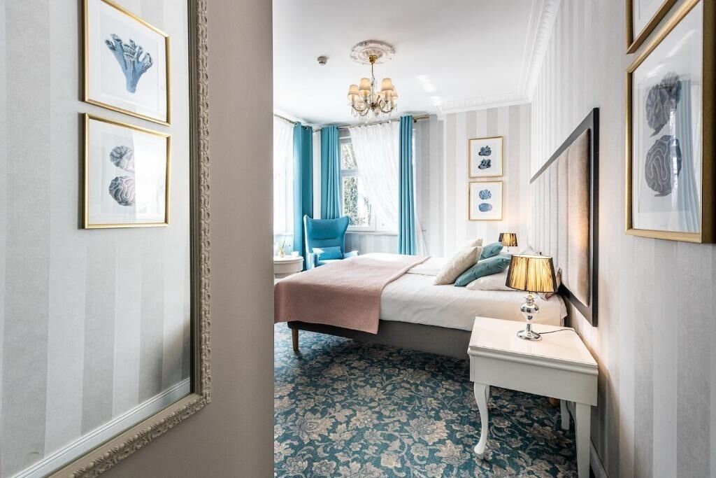 A bedroom with a bed, a nightstand, a chair, and framed artwork on the walls.