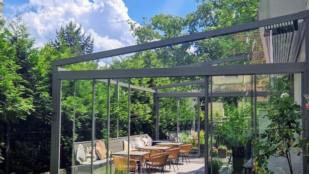 A modern outdoor patio with glass walls, a lawn, and a stone pathway. - Villa Antonina (Sopot)