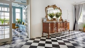 A room with a checkered floor, a wooden cabinet with a mirror, and a view through a glass door. - Villa Antonina (Sopot)