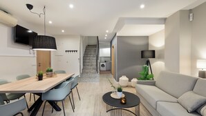 Un salon moderne comprenant un canapé, une table à manger avec des chaises, une table basse et un escalier menant à un autre niveau.