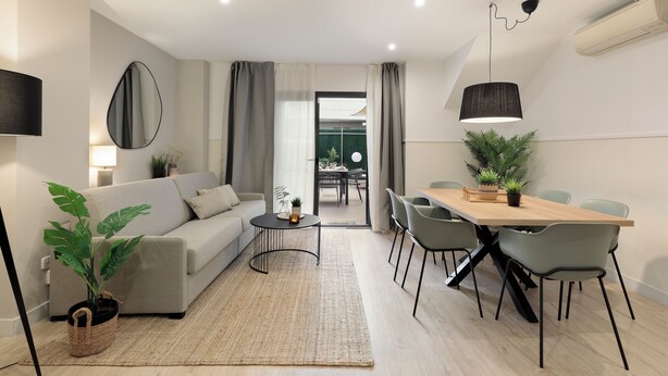Un salon moderne avec un canapé, une table à manger, des chaises et une plante en pot.