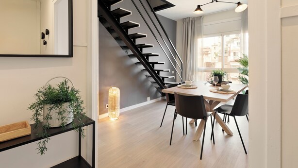 Un espace repas moderne comprenant un escalier, une table à manger avec des chaises et un luminaire suspendu.