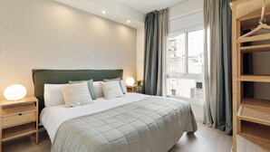 Une chambre à coucher bien rangée, avec un grand lit, des lampes de chevet, une armoire en bois et une fenêtre avec des rideaux.
