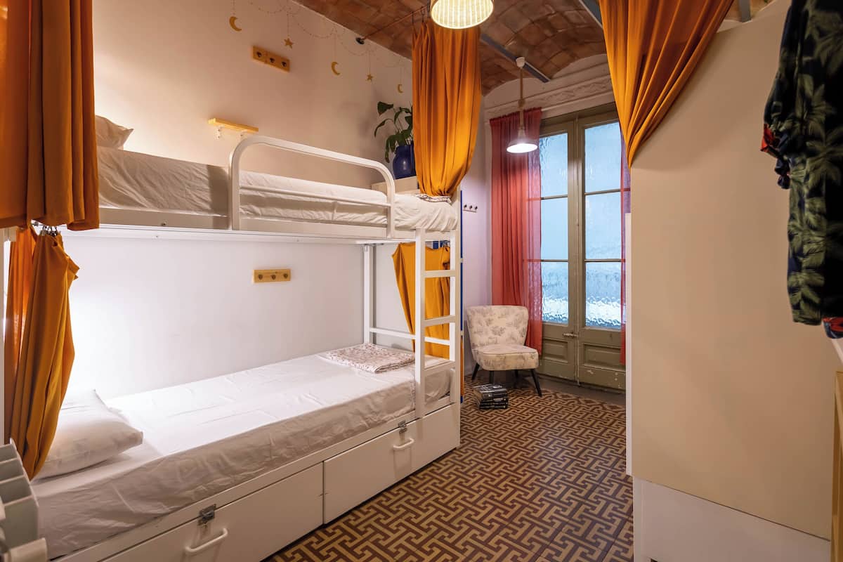 Ein Schlafzimmer mit Etagenbetten, einem Musterfußboden, einem Stuhl und einem Fenster mit Vorhängen.