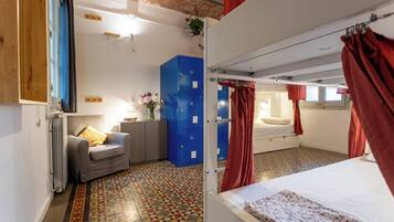 Una habitación con una cama, un sofá, un mueble azul para guardar objetos y un radiador.