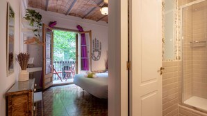 Un baño con ducha, una cama y una puerta que da a un balcón.