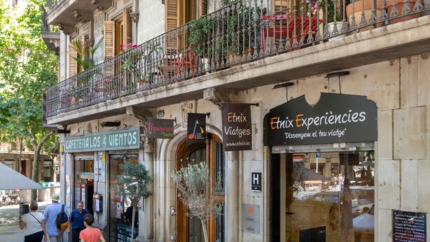 Un edificio con varios balcones, una cafetería llamada "Cafeteria Los Viñedos" y un letrero de "Ethix Experiences".