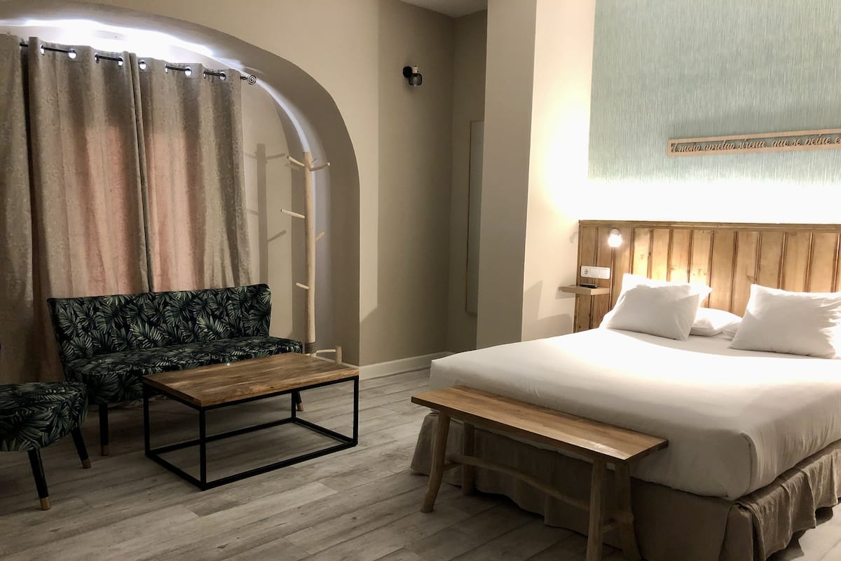 Habitació d'hotel amb un llit, una panxa, un sofà i una taula petita.