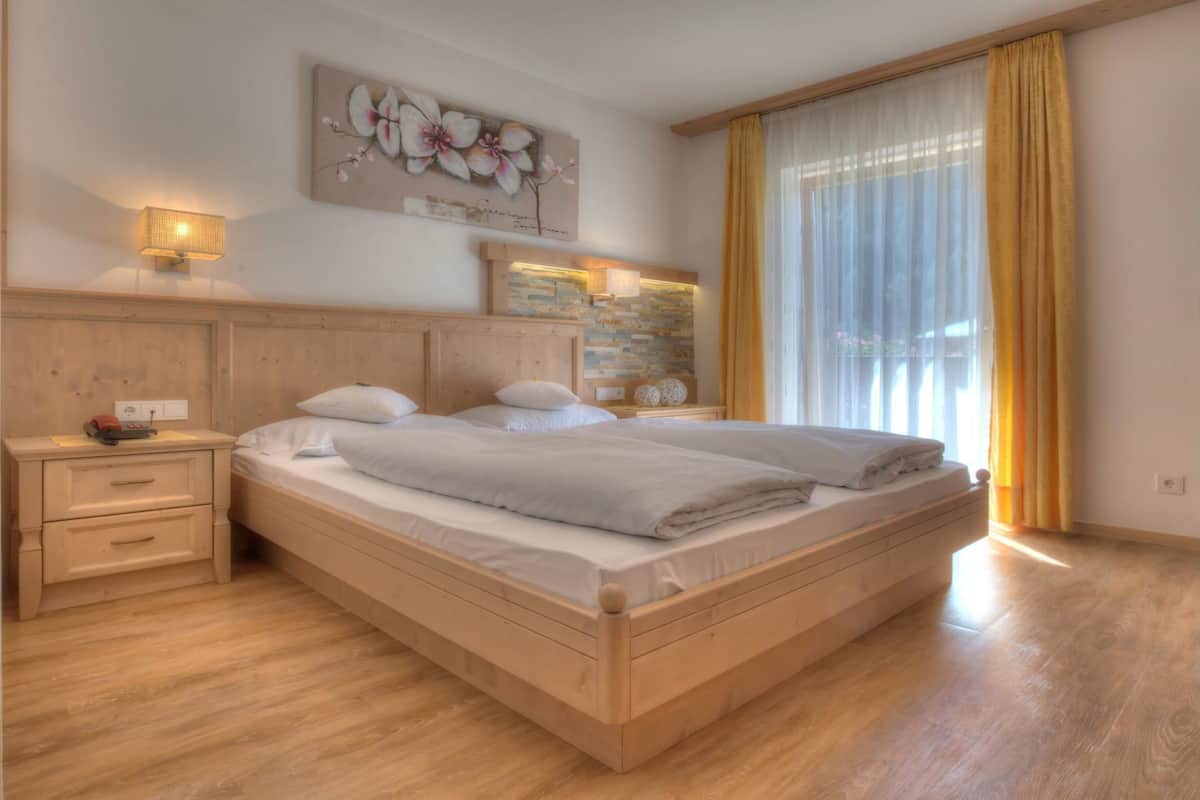 A double bed with a wooden headboard, a nightstand with a lamp, and a wall-mounted artwork.