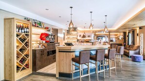 Una cocina moderna con una isla central, zona de bar, espacio para guardar vino y taburetes de bar.