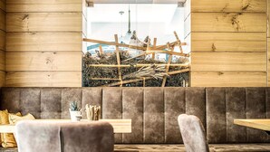 Interior de un restaurante con paredes de madera, una zona de asientos con cabinas acolchadas y vistas a un paisaje rural a través de una ventana.