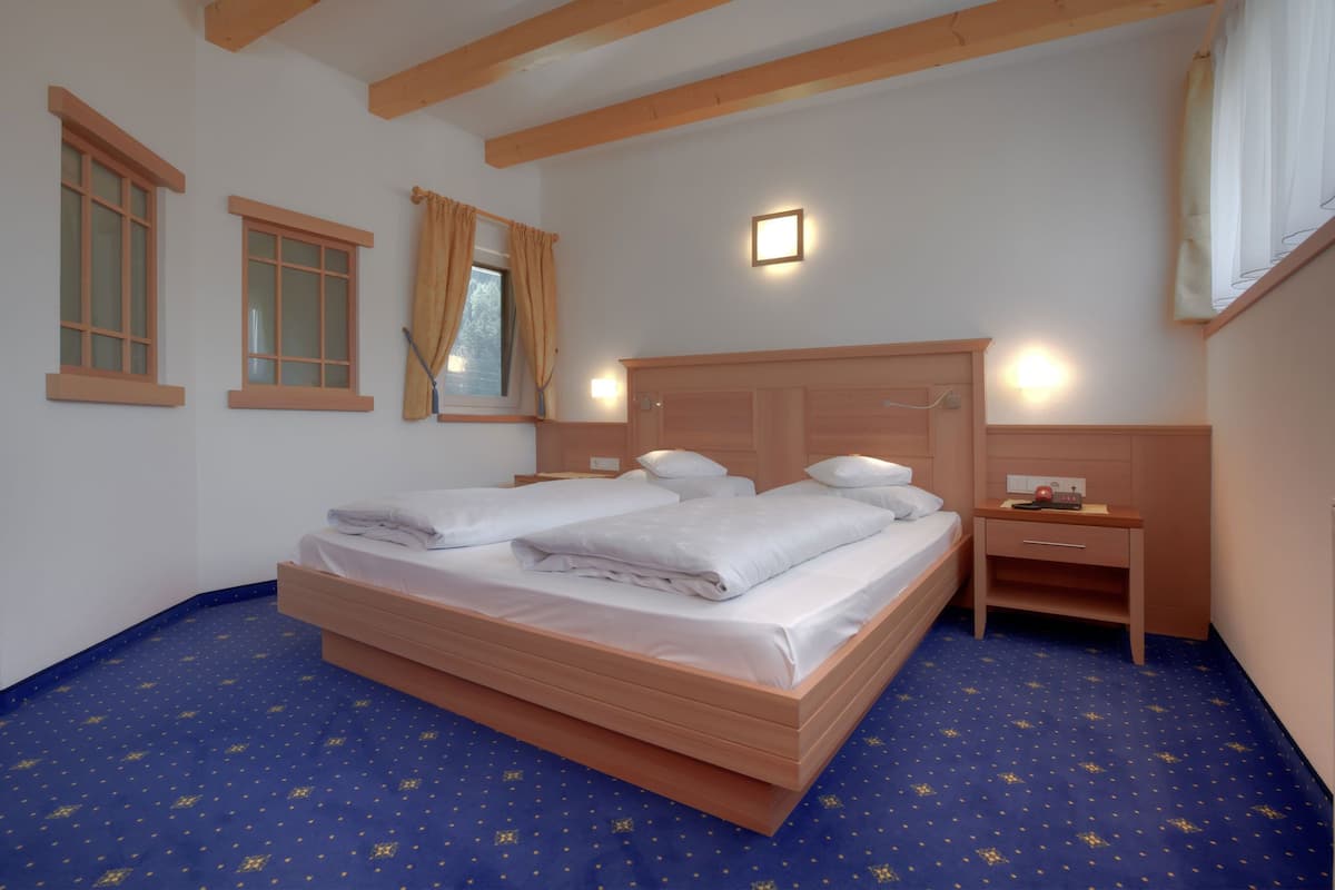 A bedroom with a large bed, two bedside tables, and a window with curtains.