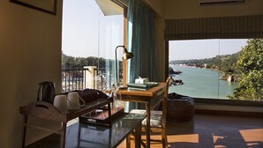 Ein Zimmer mit Blick auf einen Fluss und Hügel, ein Schreibtisch mit Lampe, ein Sessel und ein Tisch mit Tablett.