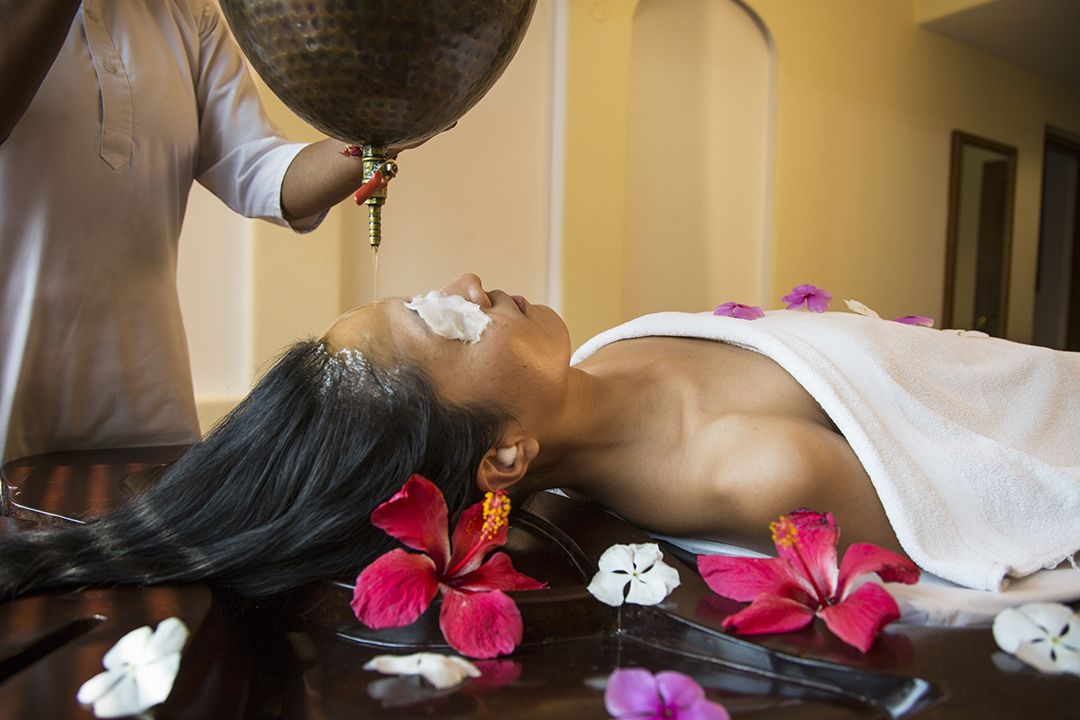 A person receiving a facial treatment with flowers and a towel on a table.