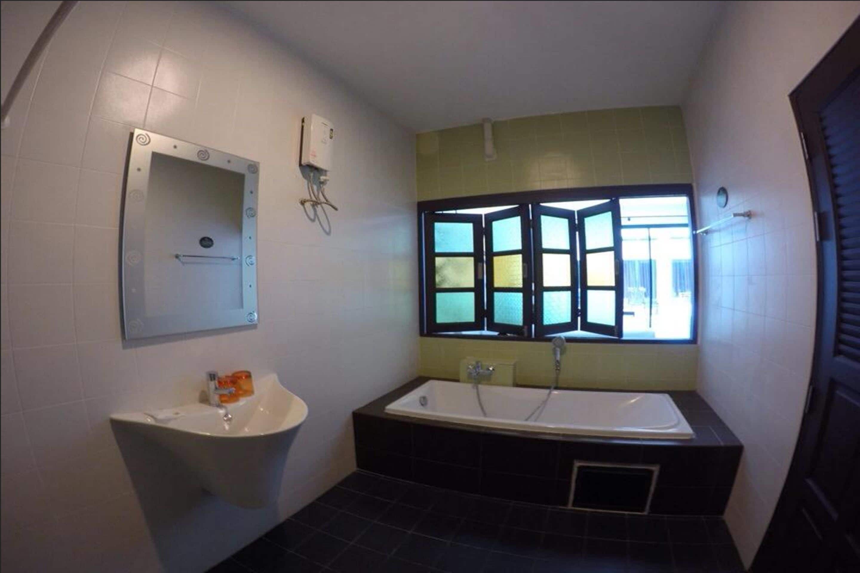 A bathroom with a bathtub, a sink, and a window with a view.