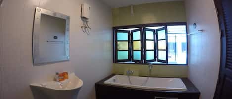 A bathroom with a bathtub, a sink, and a window with a view.