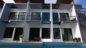 A modern multi-story building with a swimming pool in front. - Alphabeto Resort (Rawai)