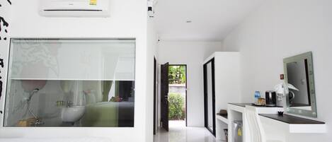 Habitación de hotel moderna con una cama grande, un escritorio con silla, televisión y baño con lavamanos y ducha.