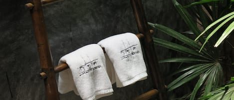 Une échelle en bambou sur laquelle sont suspendues deux serviettes blanches.