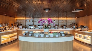 A modern breakfast bar with a central floral arrangement, surrounded by various food stations and kitchen equipment. - Bintang Kuta Hotel (Kuta)