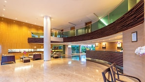 A spacious lobby with a high ceiling, a central column, and a seating area with a bench and chairs. - Bintang Kuta Hotel (Kuta)