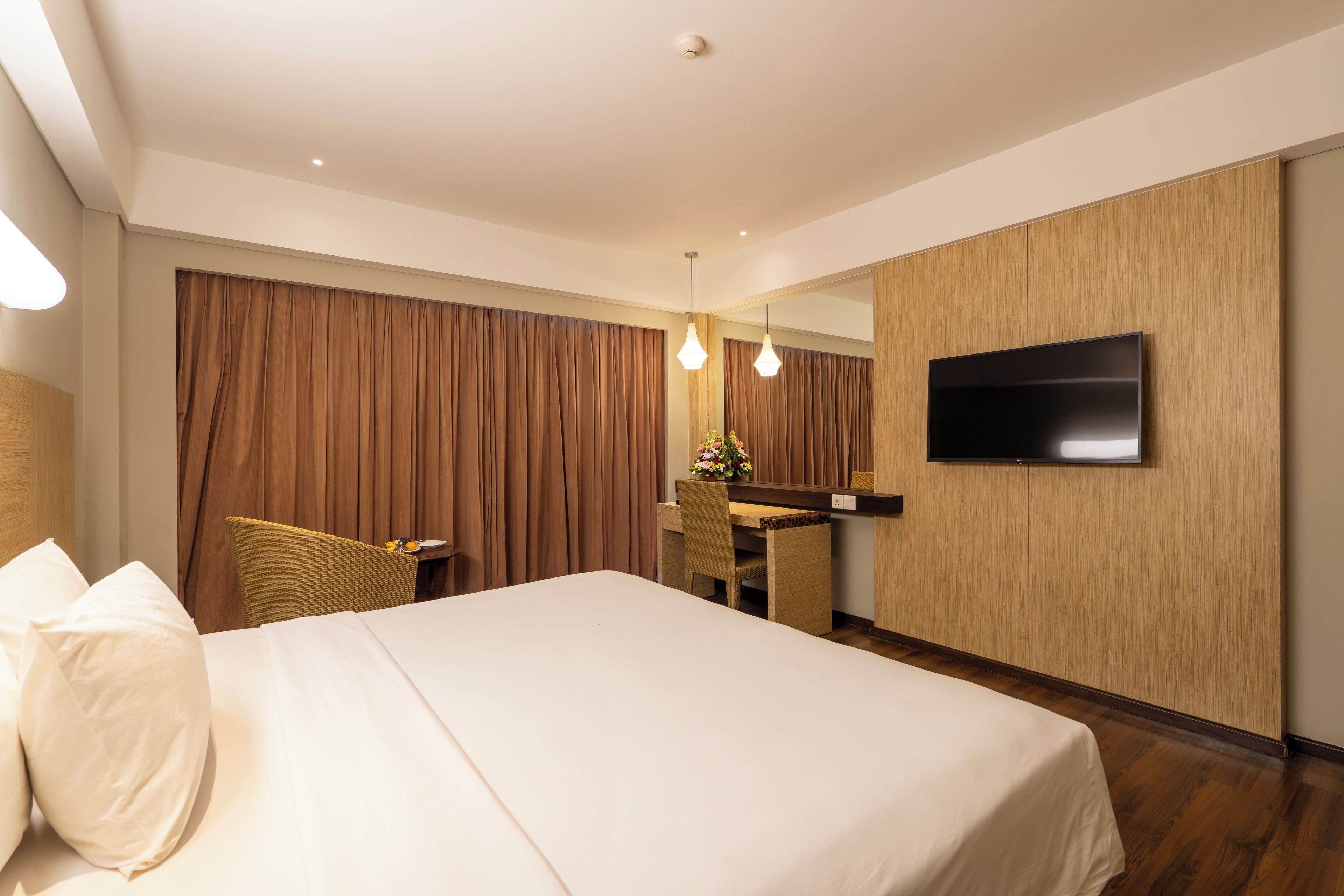 A hotel room with a large bed, a desk, a chair, a television, and a curtain.