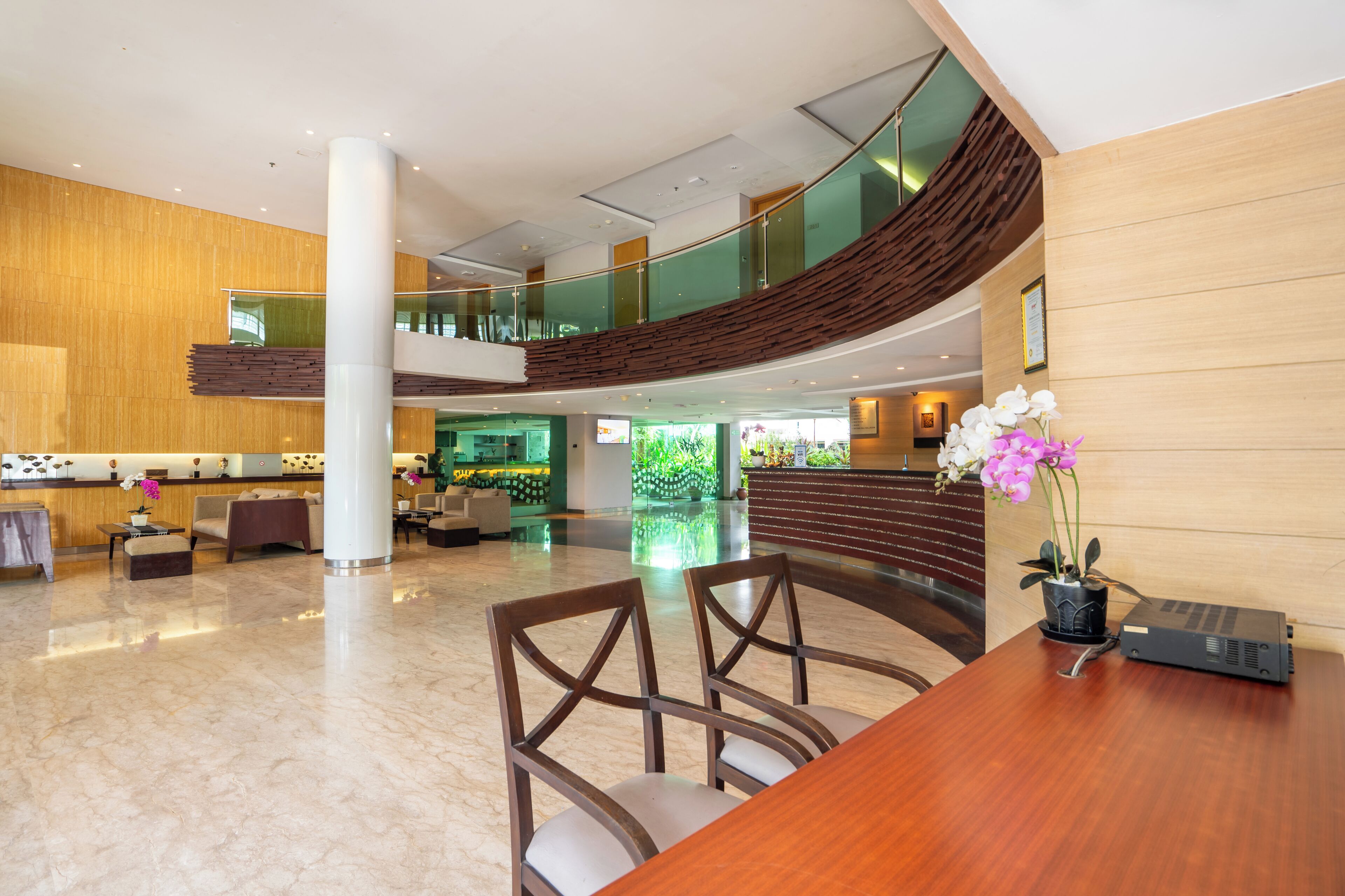 A spacious lobby with a high ceiling, a central column, and a seating area with chairs and a table.