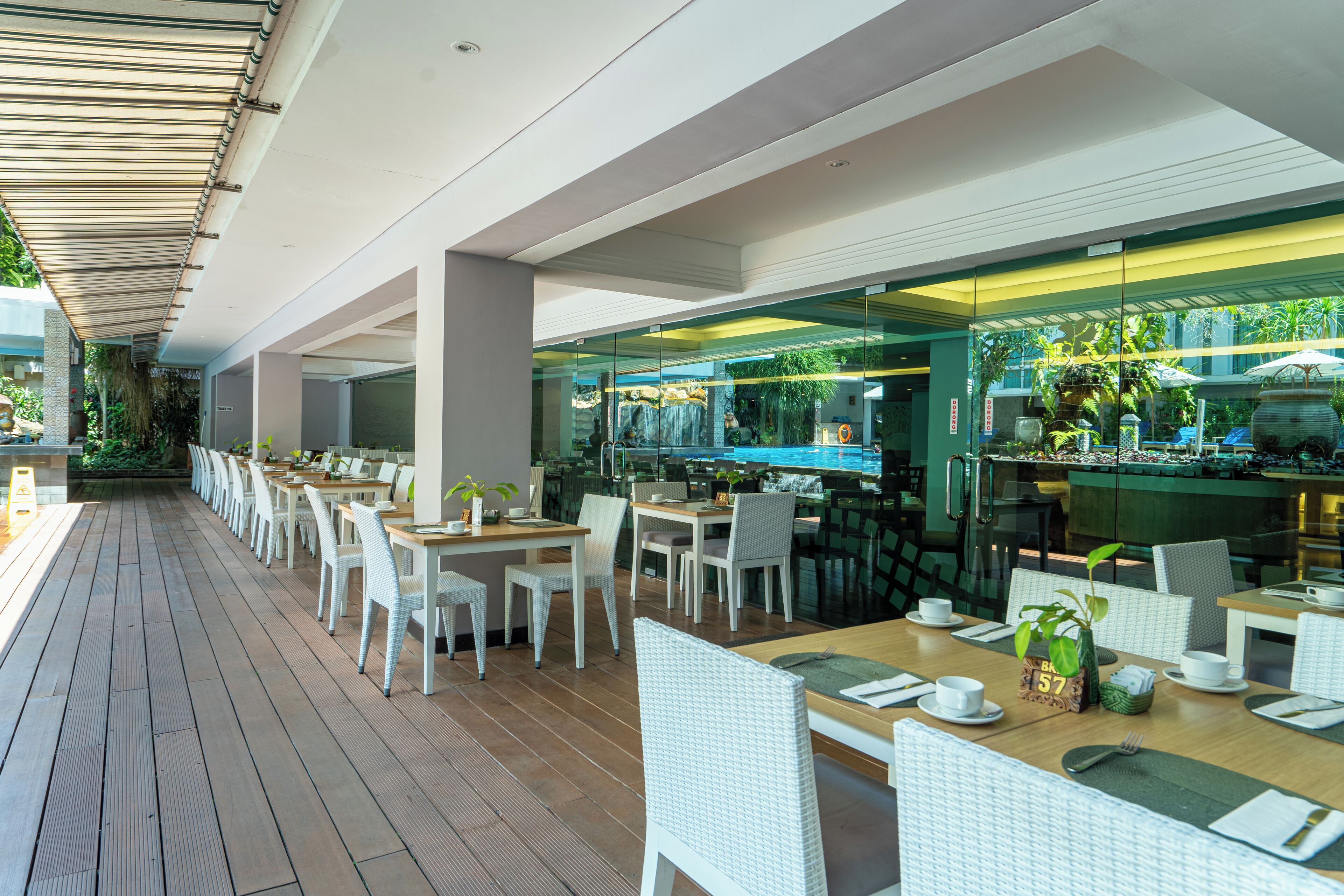 A restaurant with outdoor seating, white wicker chairs, and a wooden deck.