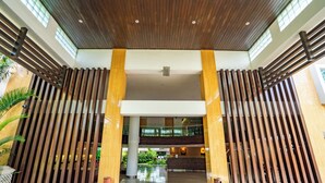 A modern building entrance with a wooden slat design, a central white pillar, and a glass ceiling. - Bintang Kuta Hotel (Kuta)
