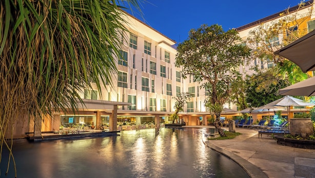 A hotel courtyard with a pool, outdoor seating, and a building with multiple floors and windows. - Bintang Kuta Hotel (Kuta)