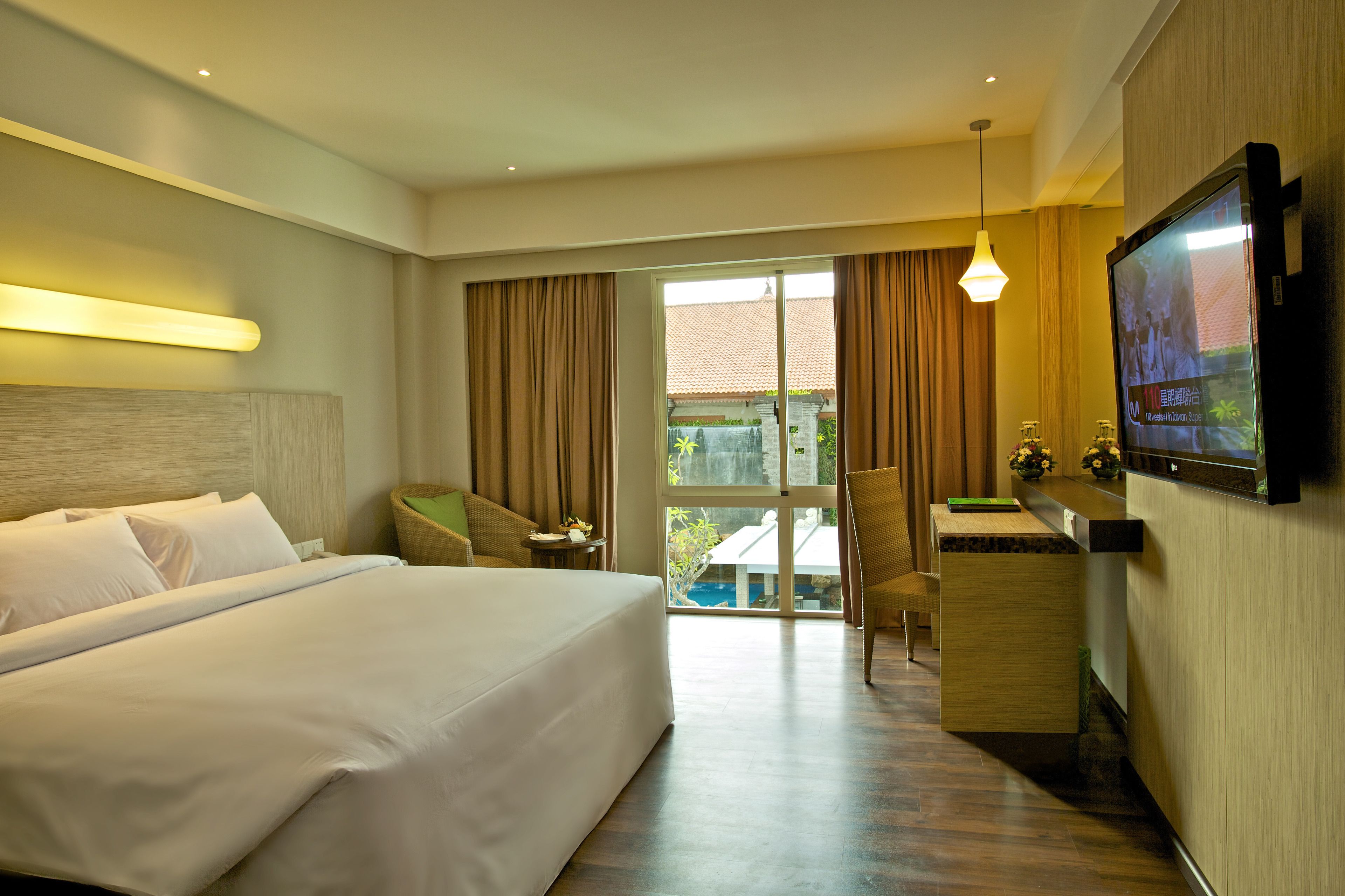 Habitación de hotel con una cama grande, un escritorio, una silla, un televisor y vistas al exterior.