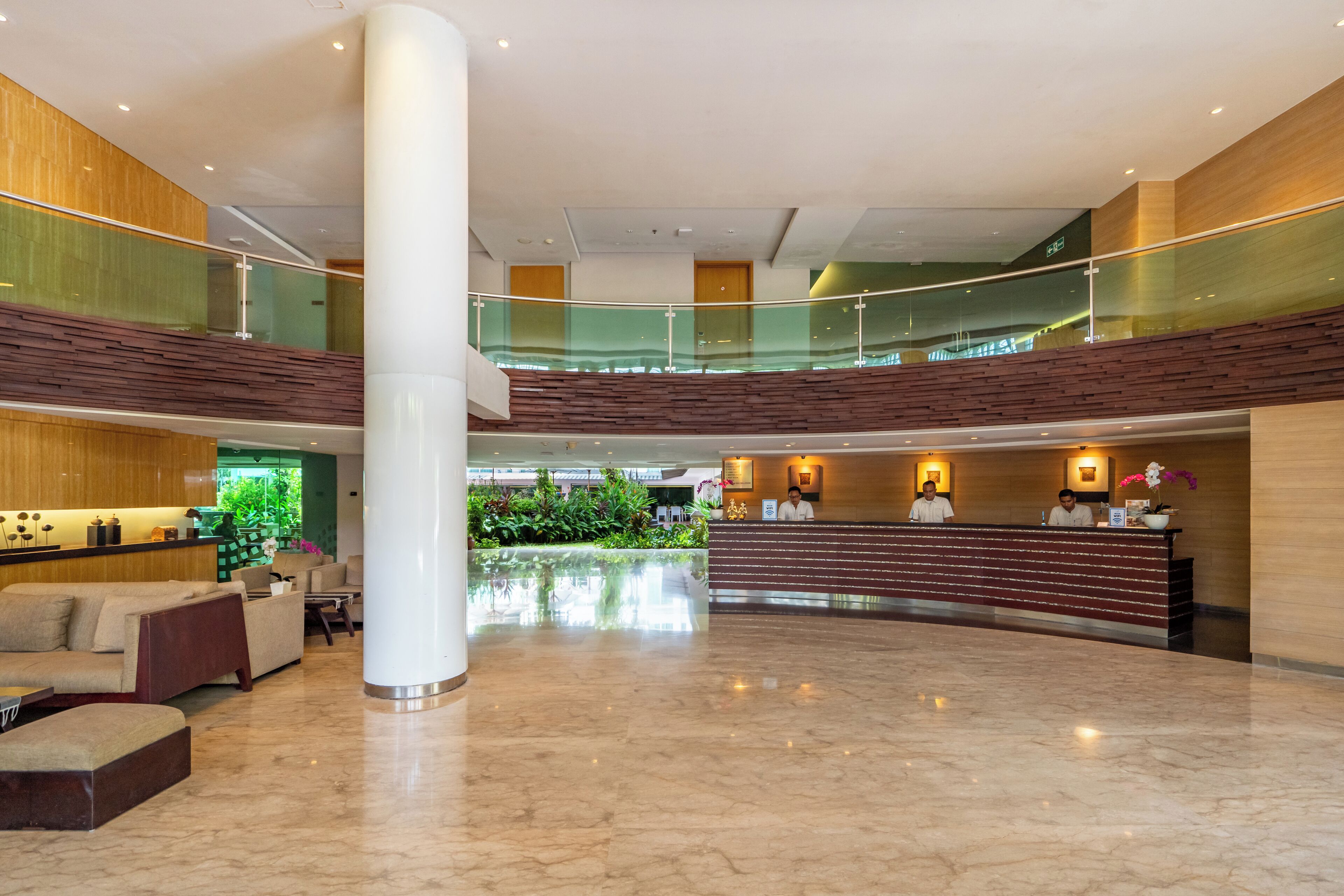 A spacious lobby with a reception desk, seating area, and a glass railing overlooking a lower level.