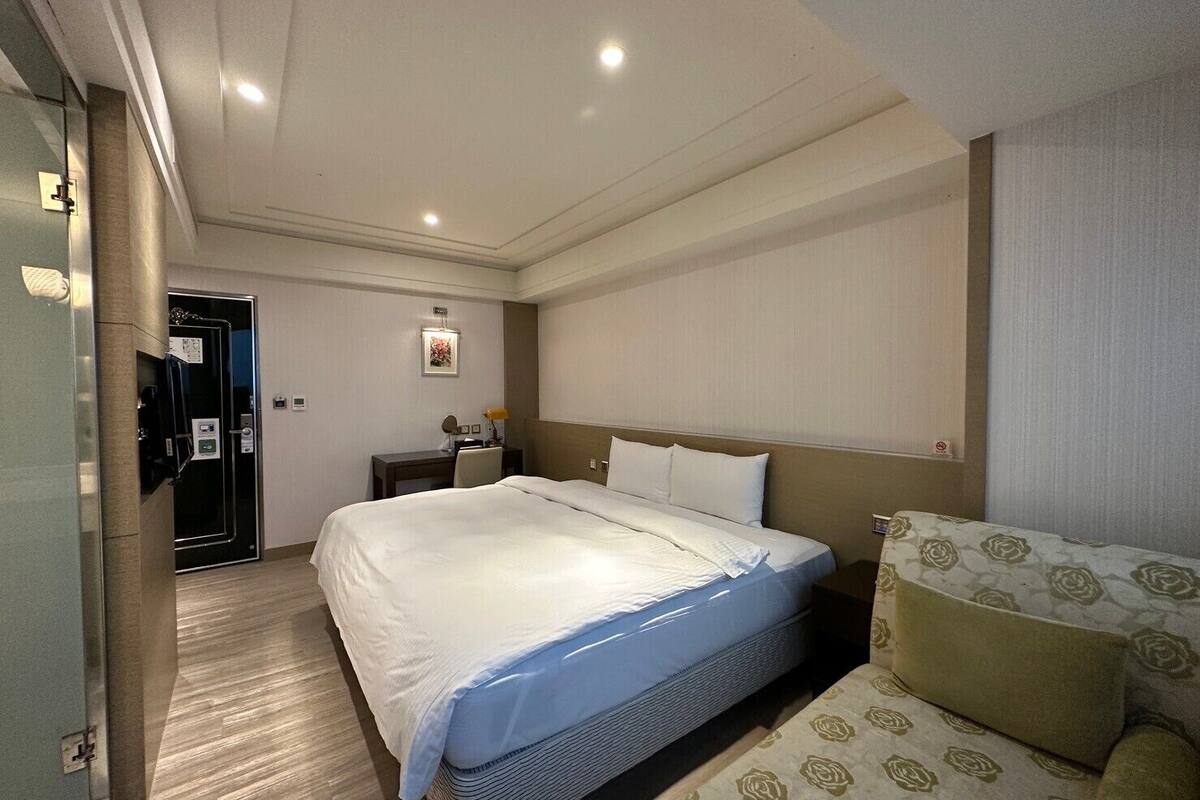 A hotel room with a large bed, a desk, and a chair.