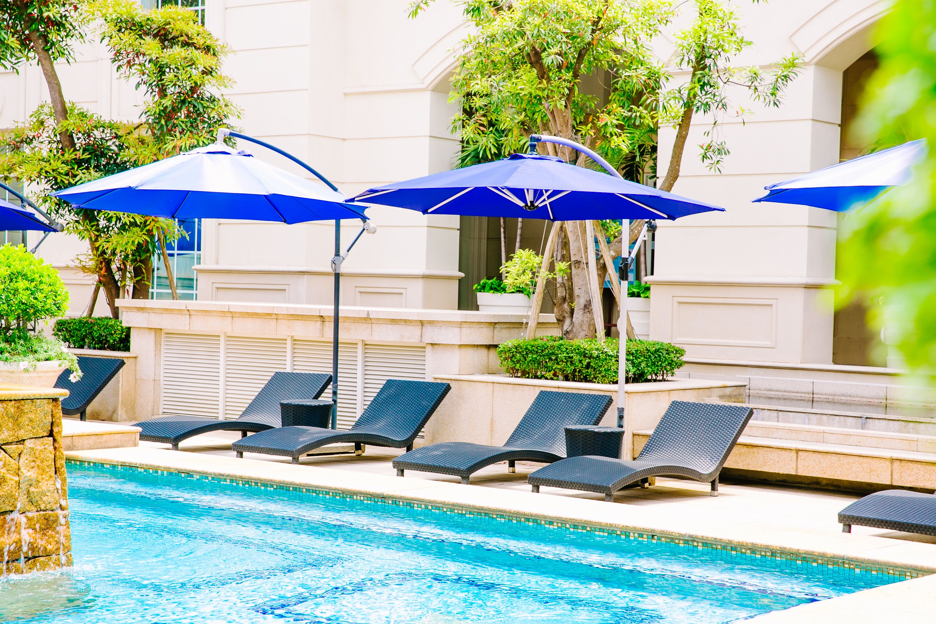 A pool area with lounge chairs and blue umbrellas.