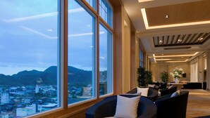 A spacious indoor area with large windows, wicker furniture, and a view of a cityscape and mountains. - RSL Cold & Hot Springs Resort Suao (Suao)